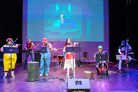 Band playing music while dressed as various retro video game characters
